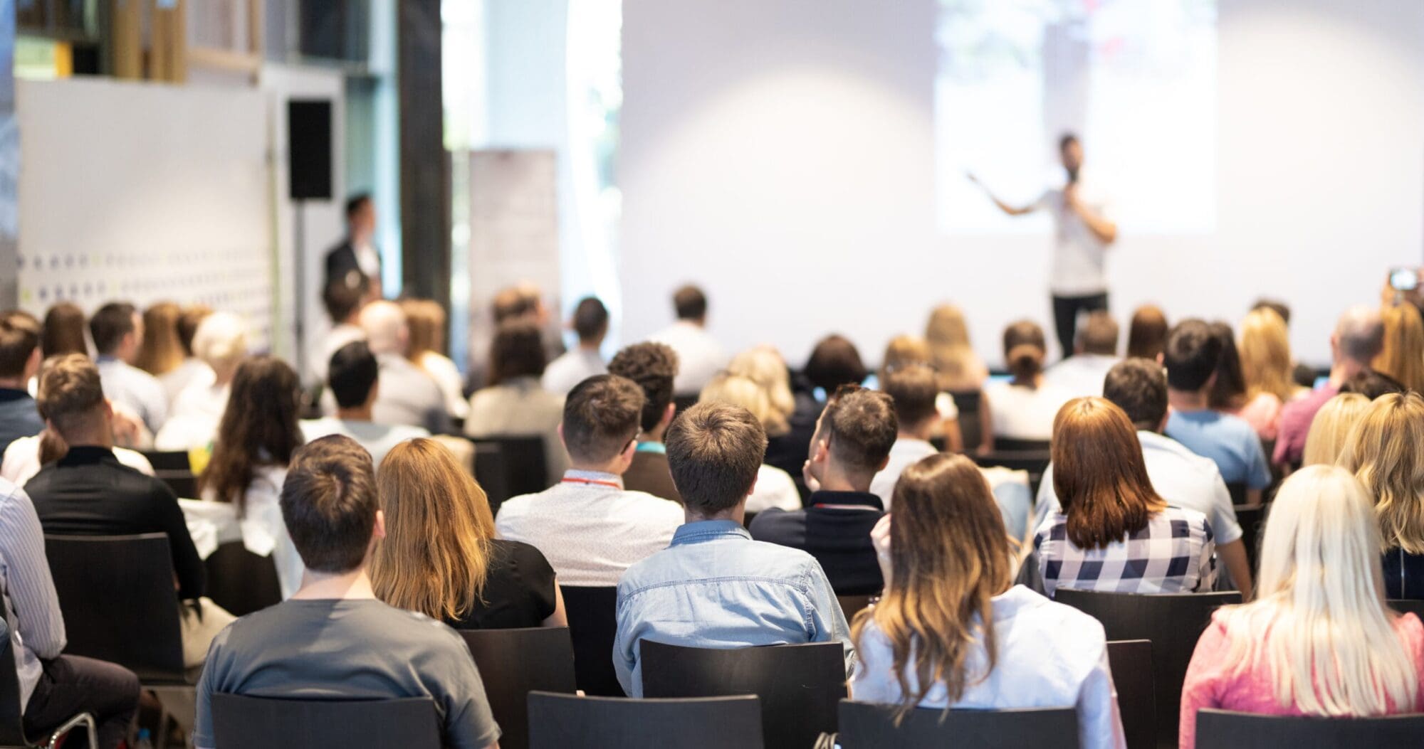 Audience attending conference presentation in modern meeting room